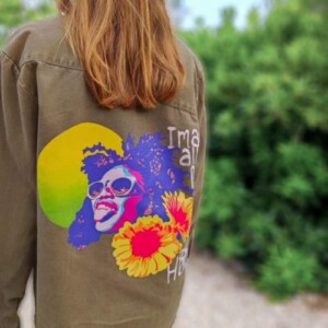 surchemise militaire Volcom surremise_militaire_vert_kaki_customisee_peinte_a_la_main_reprensentant_une_femme_afro_devant_un_soleil_et_des_fleurs_marguerites_geantes